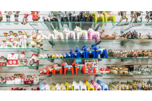 Glass shelves hanging on a wall filled with colorful knickknacks. There are small figurines of horses, people, and houses.